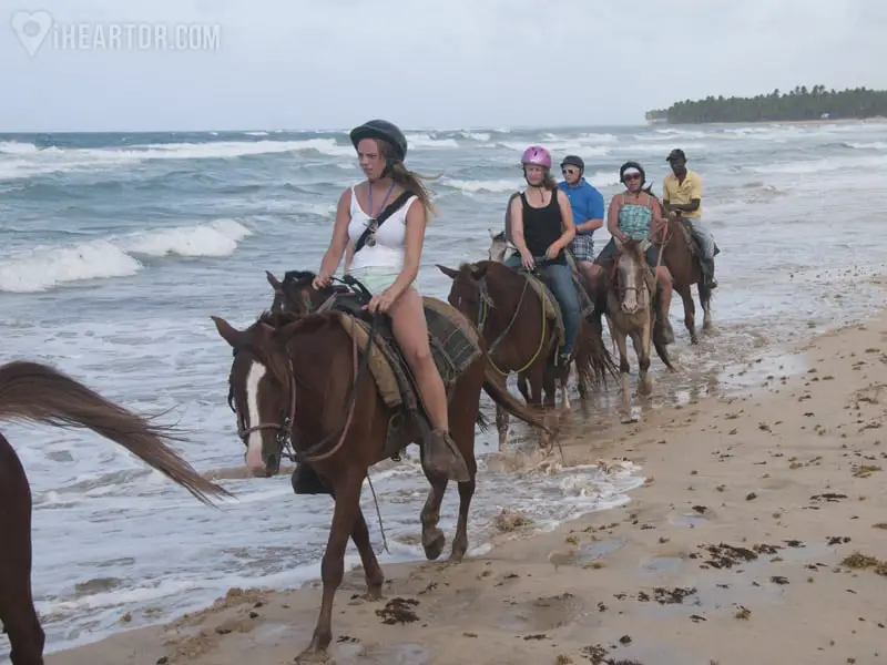 Family horseback riding on the beach