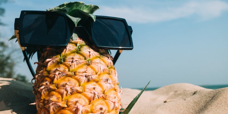 Pineapple with sunglasses on the sand